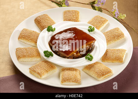 Grilled square biscuits with braised pork on white plate in restaurant Stock Photo