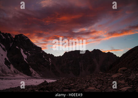 Red sunset, pink glacier and dark rocks Stock Photo