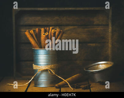 Cinnamon sticks in metal jar on wooden table, rustic tray at background, selective focus, copy space Stock Photo