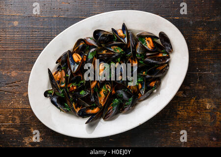 Mussels with parsley on white plate on wooden background Stock Photo