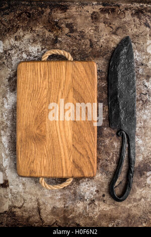 Chopping board and old knife on rustic table Stock Photo