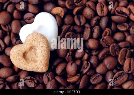 Brown and white sugar hearts lying on roasted coffee beans Stock Photo