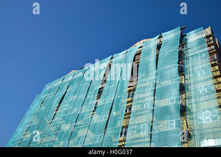 Safety net in the newly built high-rise building. Green grid on building of objects falling from a height. Stock Photo