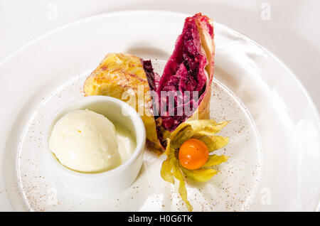 Strudel of frozen puff pastry with cherry on white plate Stock Photo