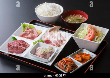 Table meal with fresh beef, pork, kimchi, rice, salald and miso soup in Japapnese style on black background Stock Photo