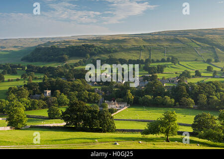 Summer evening view over picturesque Dales village of Arncliffe (church & houses) nestling in valley under sunlit hills - North Yorkshire, England, UK