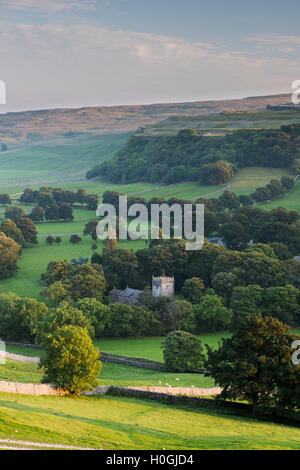 Summer evening view over church (& tower) in picturesque Dales village nestling in valley under sunlit hills - Arncliffe, North Yorkshire, England, UK