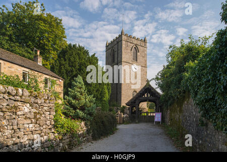 View up pathway, leading to the lychgate and entrance to St. Mary's Church (with tower) - Kettlewell, North Yorkshire, England. Stock Photo