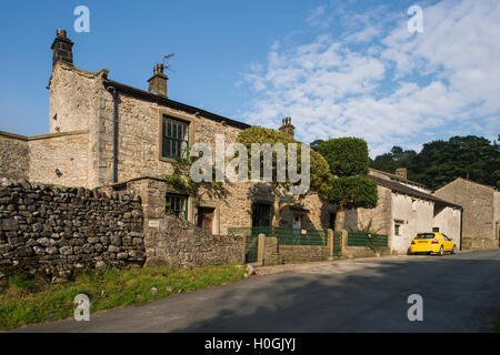 Country lane view of a traditional, stone-built house with fancy railings and attached barn - Kettlewell, Yorkshire Dales, GB. Stock Photo