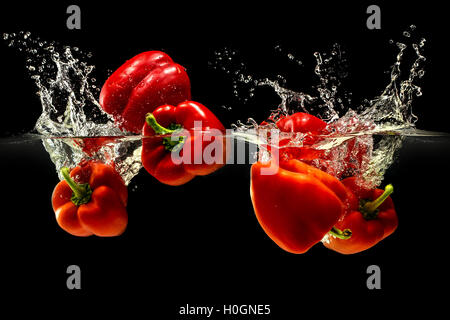 Group of bell pepper falling in water on black Stock Photo