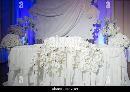 Beautiful restaurant interior table decoration for wedding. Flower . White orchids in vases. luxury candleholders Stock Photo