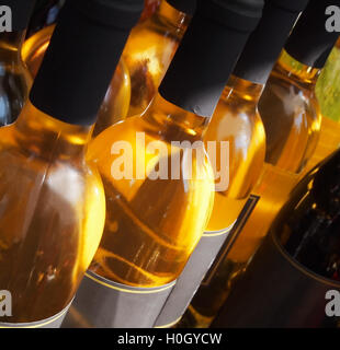Close up on the top and necks of a row of white wine bottles on a table outside. Stock Photo