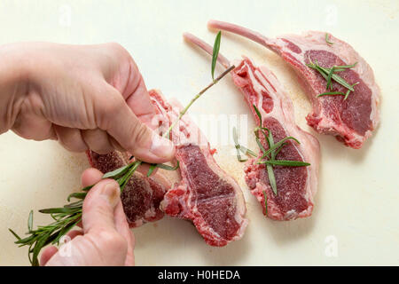 Mixing rosemarry with fresh salted beef for roasting in the kitchen Stock Photo
