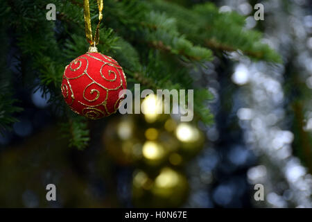 Christmas decoration. Red Christmas ball hanging from a xmas tree. Golden balls and tinsel background. Stock Photo