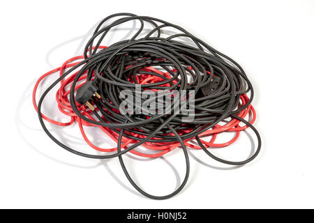 Studio shot of untidy pile of rolled red and black electric extension cables on white background Stock Photo