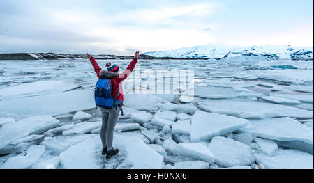 Woman standing on ice floe, Jökulsárlón glacier lagoon, southern edge of Vatnajökull, Southern Region, Iceland Stock Photo