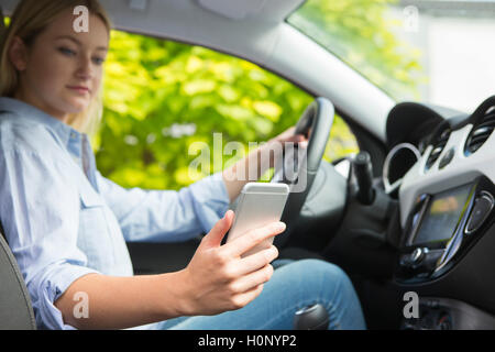Woman In Car Texting On Mobile Phone Whilst Driving Stock Photo