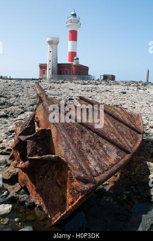 Fuerteventura: the El Toston Lighthouse, whose original structure was opened in 1897 in the northwest of the island, seen through a rusty shipwreck Stock Photo