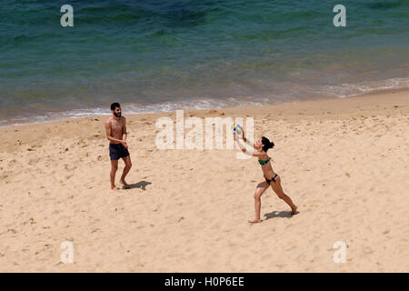 Overhead view of a young man and woman playing volleyball on the beach near the ocean Stock Photo