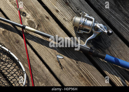 Fishing rod, reel, and net on a wooden landing beside a Vermont lake Stock Photo