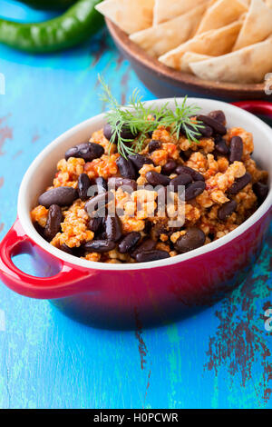 Homemade spicy stew with chili peppers, meat, and kidney beans. A pot of chili con carne served with corn tortilla chips Stock Photo