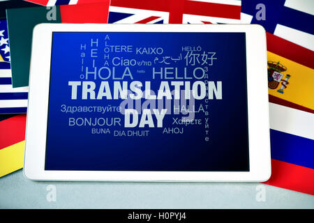 the text Translation Day in the screen of a tablet computer, and the word hello in different languages, surrounded by flags of d