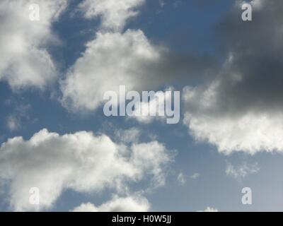 Cloudy sky with blue bits sticking out, white clouds and black clouds, silver lining Stock Photo