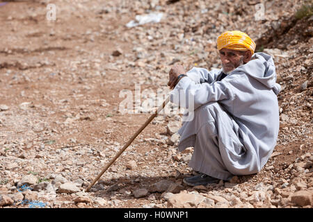 Atlas Mountains, Morocco.  Market Scene in Village near Dades Gorge.  Man Resting with his Walking Stick. Stock Photo