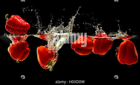 Group of bell pepper falling in water on black Stock Photo