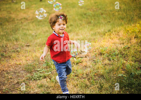 Little boy playing in the park with bubbles Stock Photo