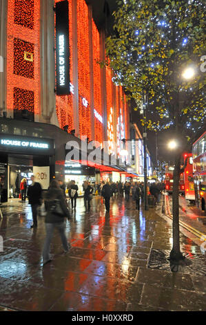 House of Fraser department store with shoppers in UK Oxford street with Christmas lights reflections rainy evening for shopping in London West End Stock Photo