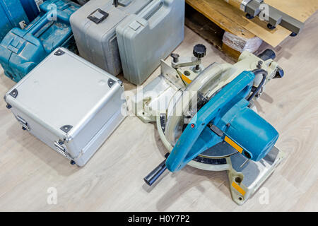 Various plastic tool boxes are on laminate floor with a lot of equipment for furnishing in workshop. Stock Photo