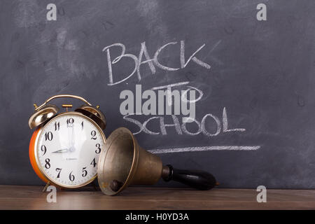 Old bell and alarm clock against a blackboard Stock Photo