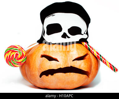 halloween holiday traditional scary smiling orange pumpkin in black skull hat and candys isolated on white background close up Stock Photo