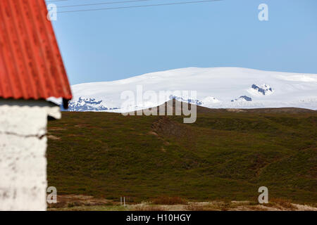 red painted corrugated metal roof on a farm outbuilding in Iceland with view of katla and myrdalsjokull glacier Stock Photo