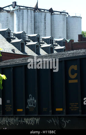 Cargo train passing by the abandoned Piedmont Flour Mill and Silo buildings on Jefferson Street in Lynchburg, Virginia, USA Stock Photo