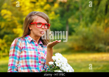 Young woman sends an air kiss in a public park. Flirt. Outdoor Activities on a sunny day. Stock Photo