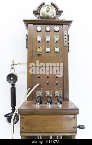 Old telephone hanging on wall pegs, communication Stock Photo