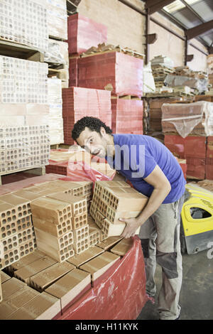 Shop worker carrying bricks, construction Stock Photo
