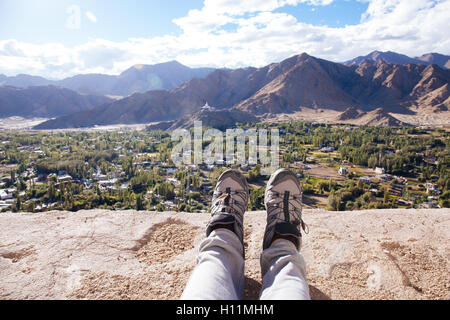 Traveler's boots relaxing and resting his feet on high mountain trekking and ancient town scene and adventure Stock Photo