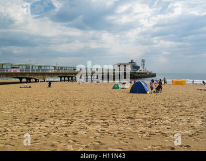 Tourists on lovely sandy beach by Bournemouth Pier stretching into Poole Bay Dorset England UK a very popular seaside town Stock Photo