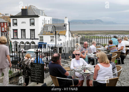 Seniors people sitting at tables outside having afternoon tea at restaurant in the seaside town of Lyme Regis, Dorset, England UK    KATHY DEWITT Stock Photo