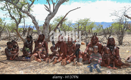 Group of Himba women and children sitting in their village in the Kunene region of Namibia Stock Photo