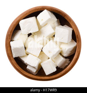 Greek Feta cheese cubes in a wooden bowl on white background. Cubes of a brined curd white cheese made in Greece. Stock Photo