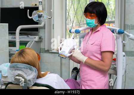 Female dentist examining patients teeth in the dentists chair Stock Photo