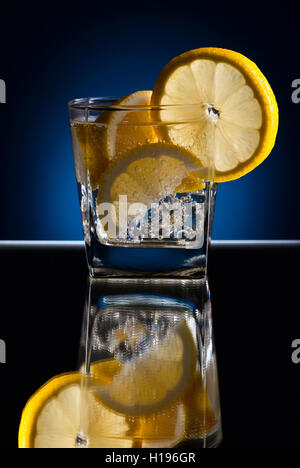 Gin with tonic; ice and lemon on a reflective background Stock Photo