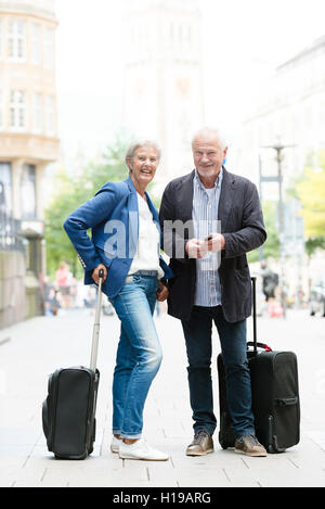 Senior couple with  suitcases and cell Stock Photo