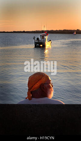 Stunning sea sunset, man watching the sunsetting on the sea and boats, Mudeford quay, Dorset, UK. Stock Photo