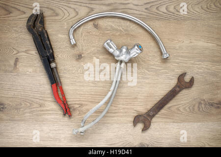 Rusty old plumbing tools and tap on wooden background Stock Photo