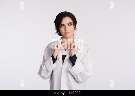 Woman doctor holding up her collar and standing against a white background Stock Photo